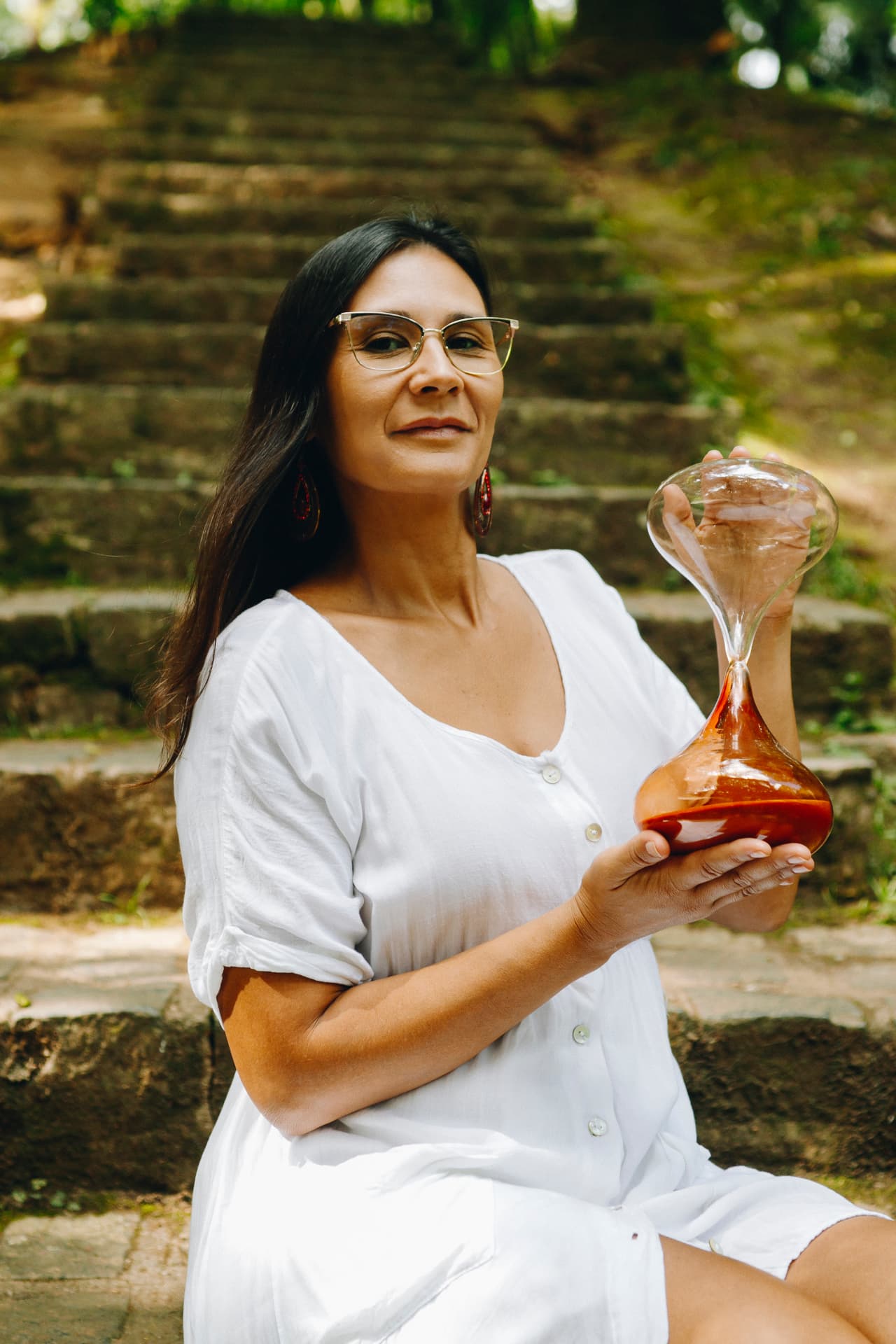 Bruna Magno segurando uma ampulheta ao ar livre