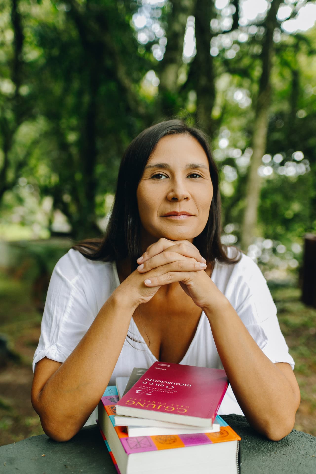 Bruna Magno diante de livros em uma área verde