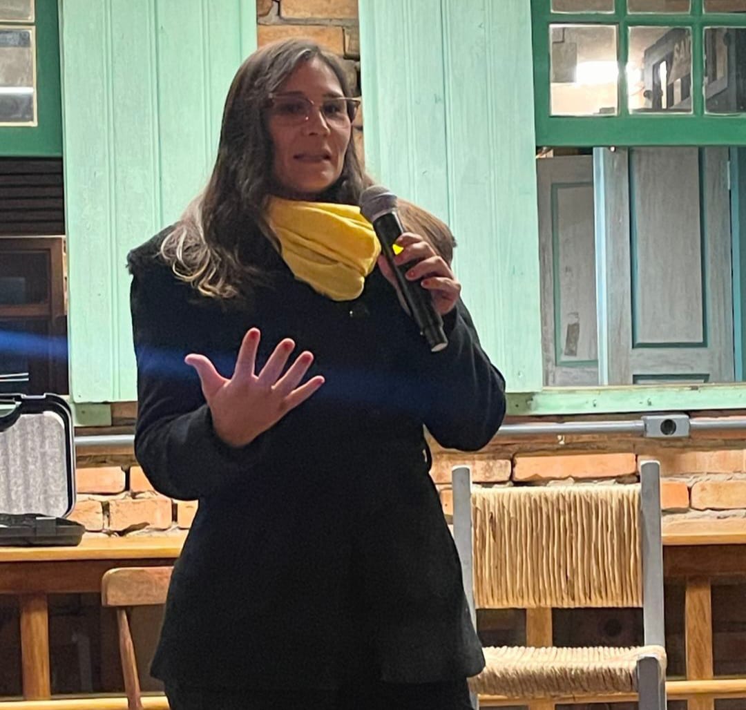 Bruna falando ao microfone em um evento