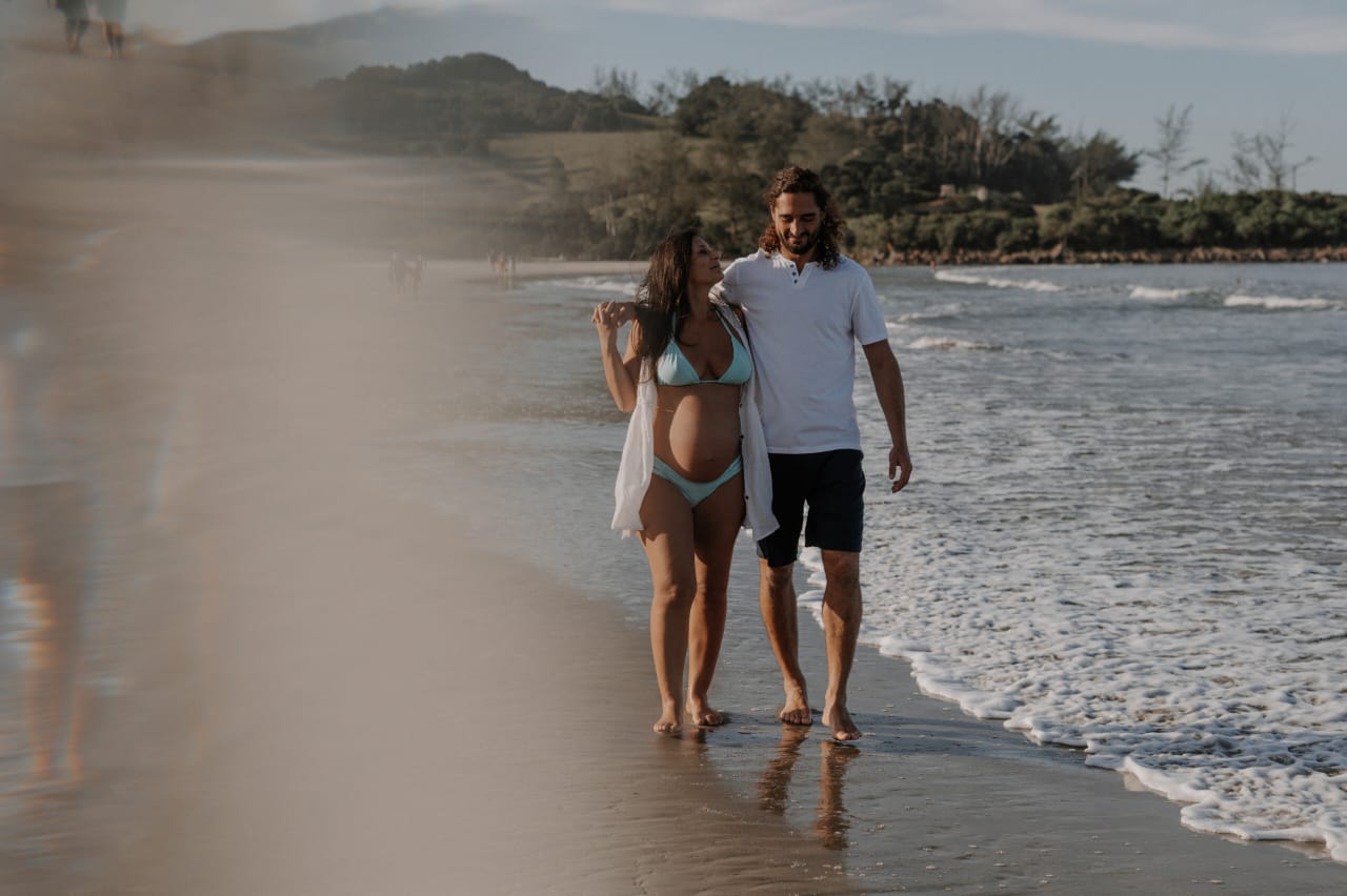 Bruna caminhando na praia com seu companheiro